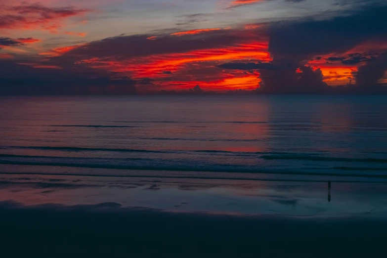 an empty beach next to some water and clouds