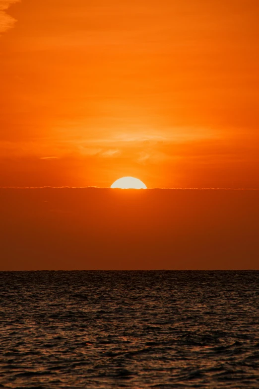 the sun is setting over the ocean as seen from the water