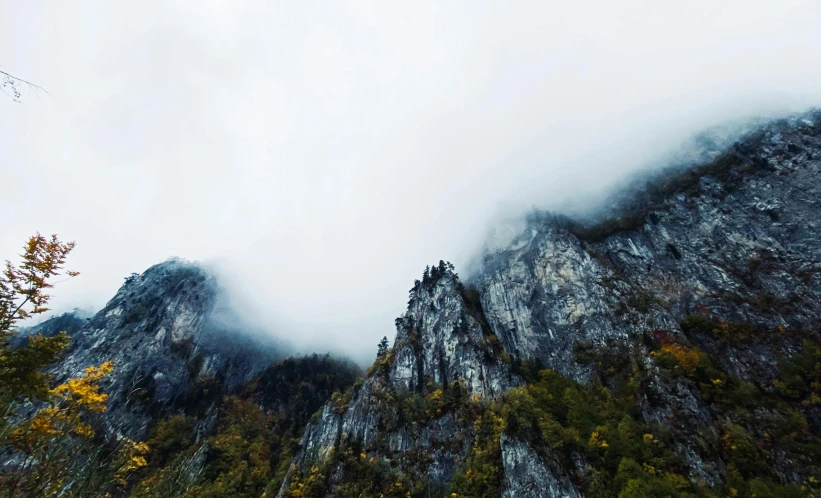 the view of fog and low hanging clouds above a rock face