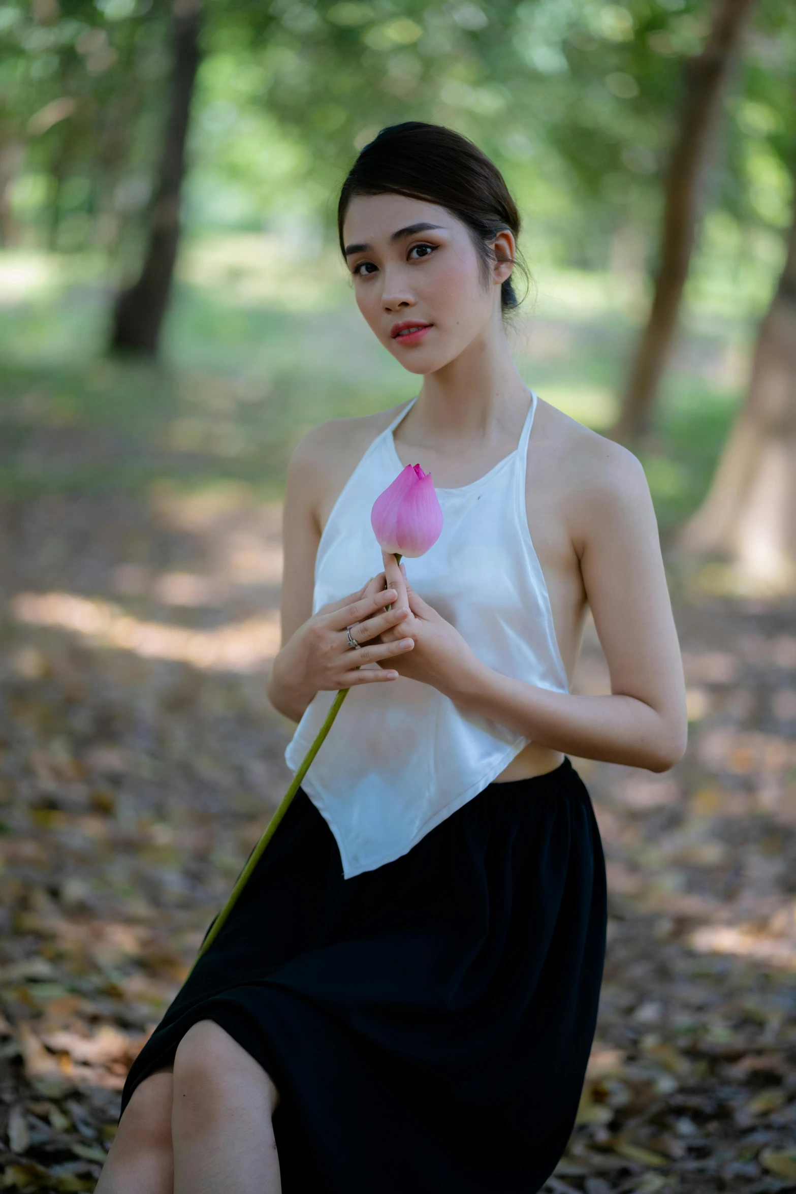 a woman sitting down holding a pink flower