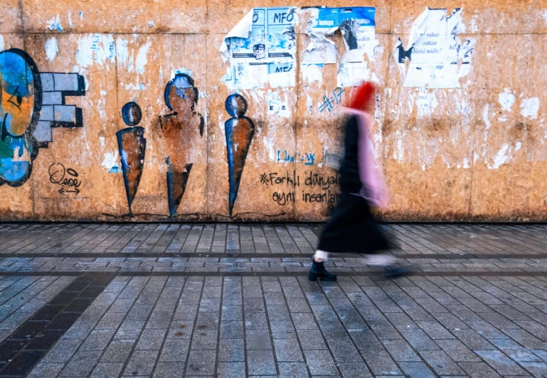 a woman walking past a wall with graffiti