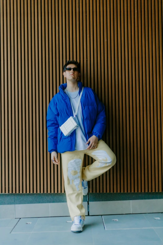 a man poses against a wall in front of a wooden wall