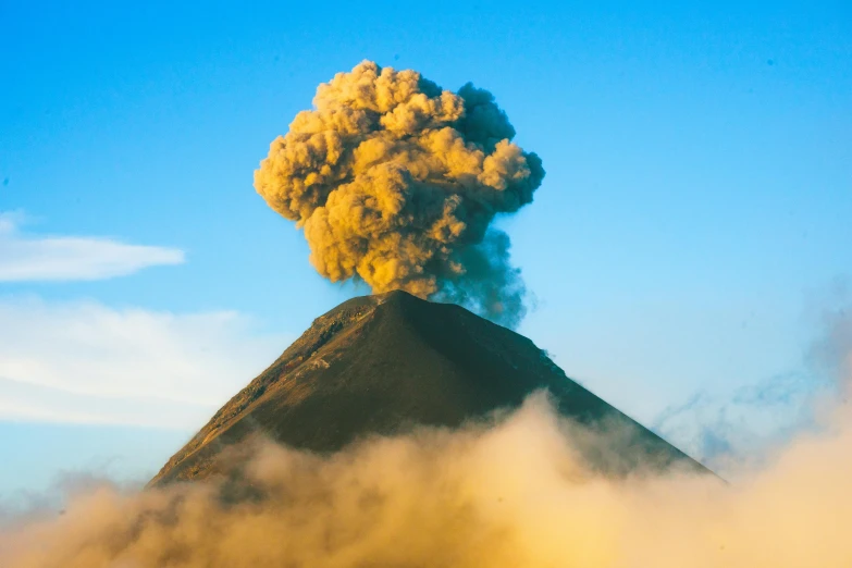 a cloud of smoke billows above a mountain peak