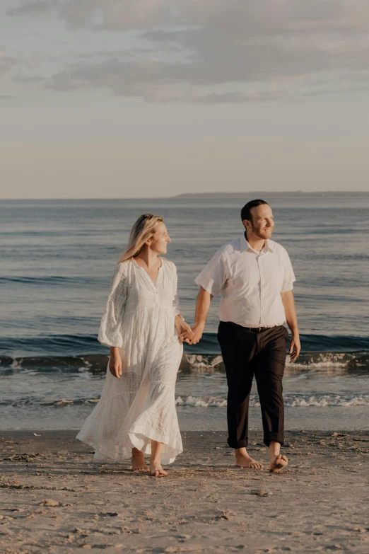 the couple is walking down the beach holding hands