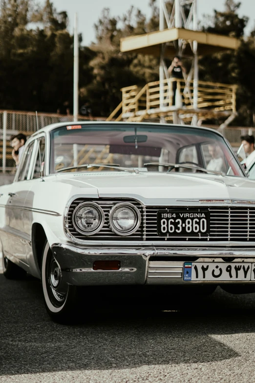 a classic white car sits at an antique show