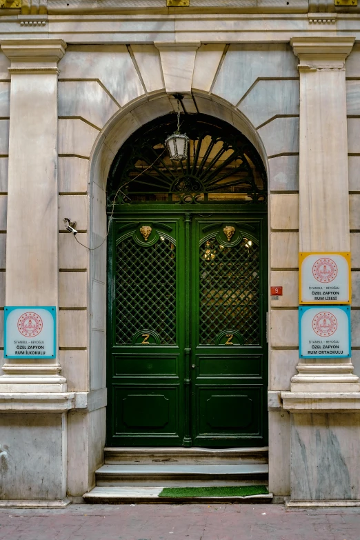 a green double door is displayed in front of an ornate building