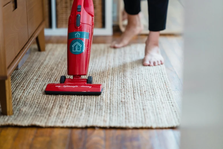 a woman that is standing on a rug with a vacuum