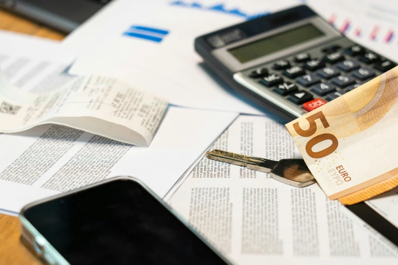 a calculator, pen, calculator and paper towels are placed on a table