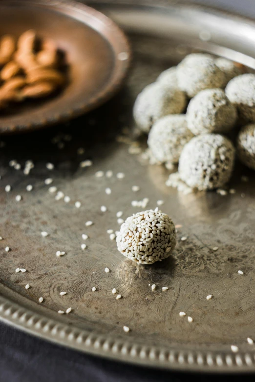 some sprinkled balls on a plate with a plate of cookies behind them