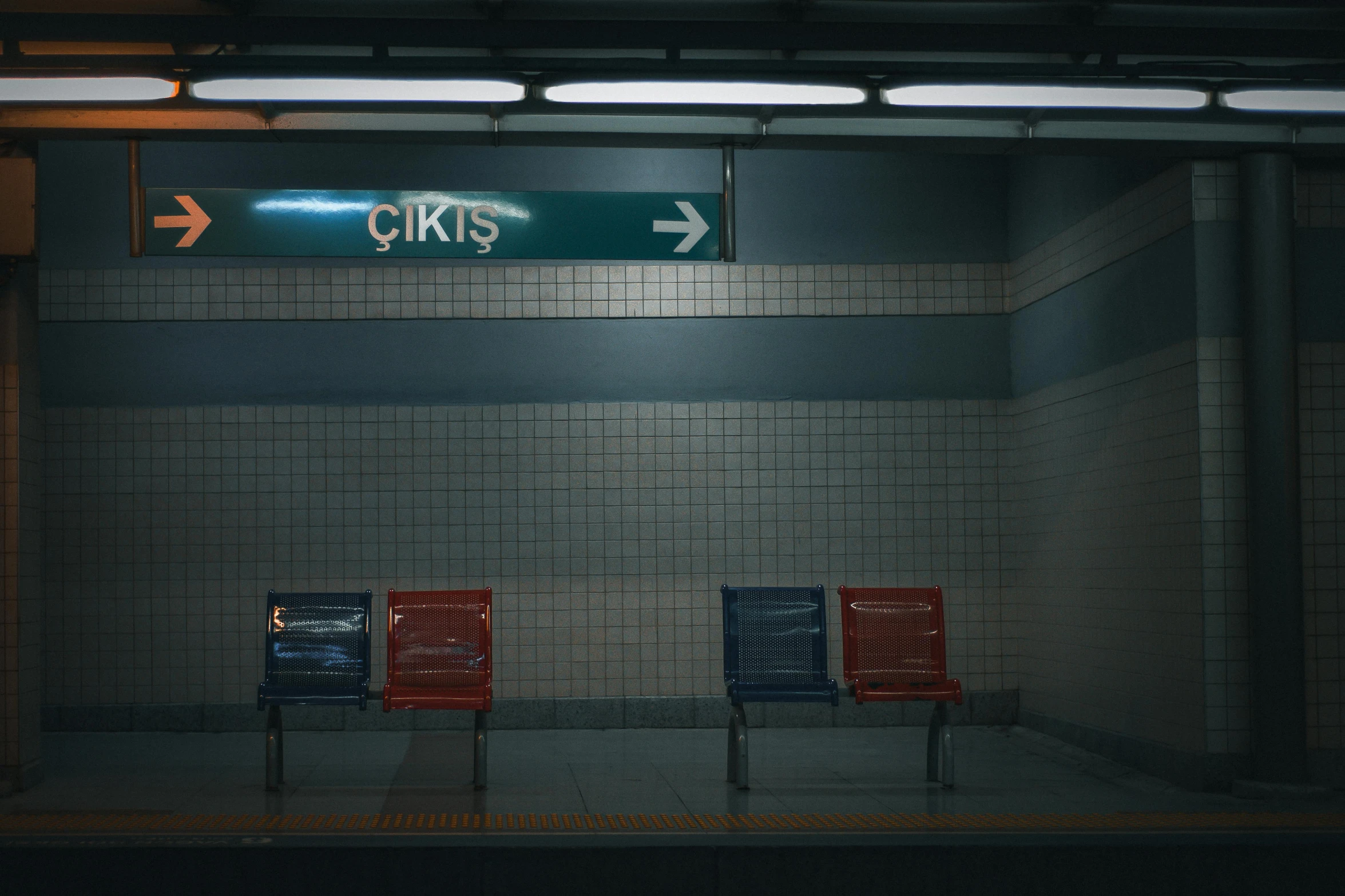 two red and blue chairs sit by a metal sign