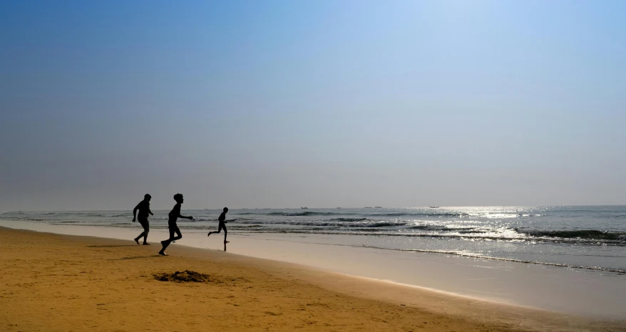 a couple of people standing on top of a sandy beach