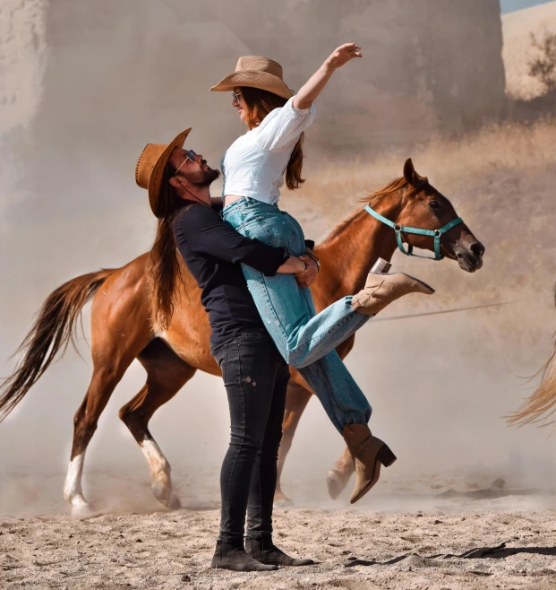 a man holding a young woman as they ride on top of horses