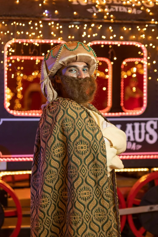 a man in an indian hat and cape wearing blankets in front of a train