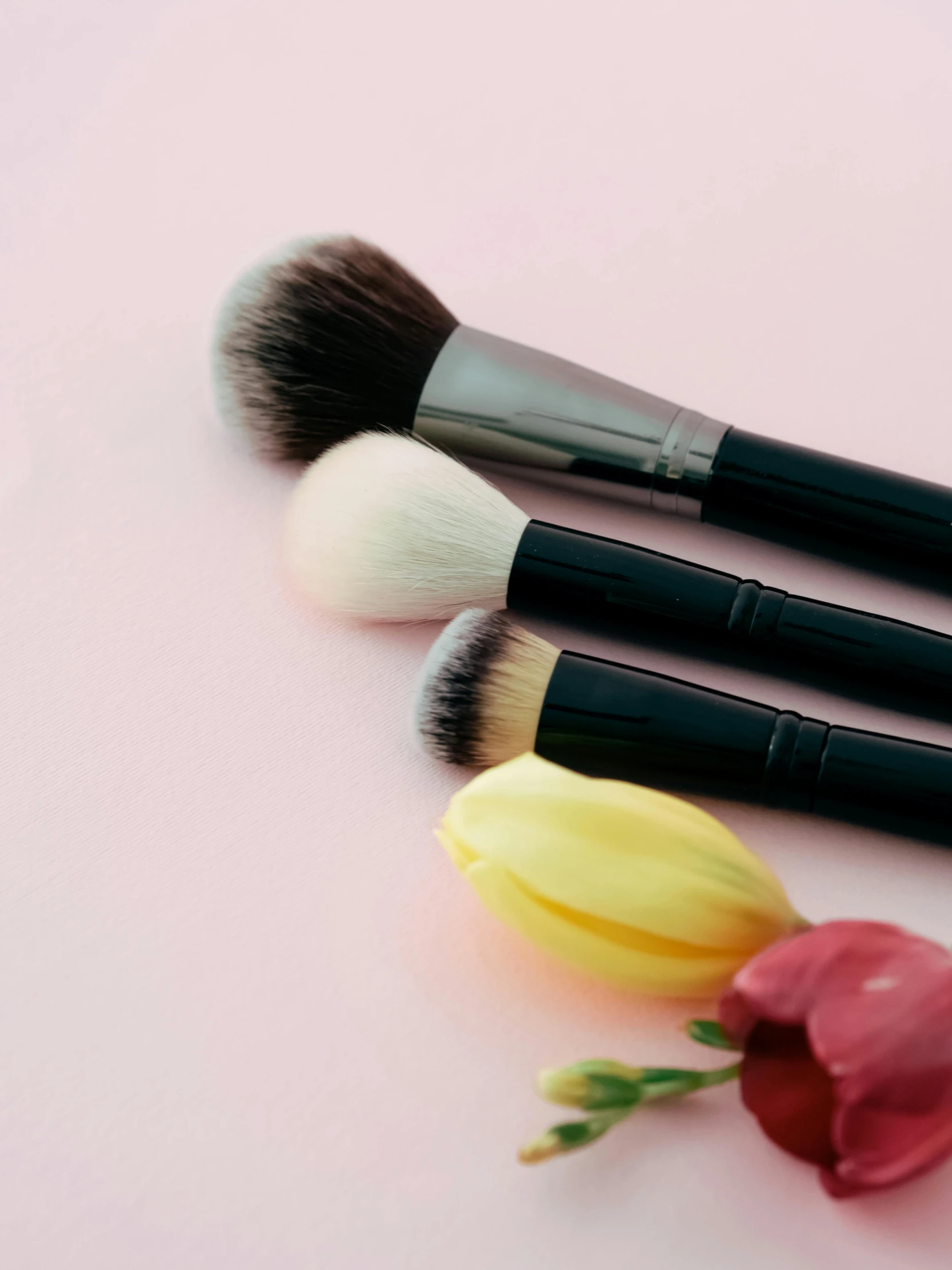 a bouquet of flowers and three cosmetic brushes