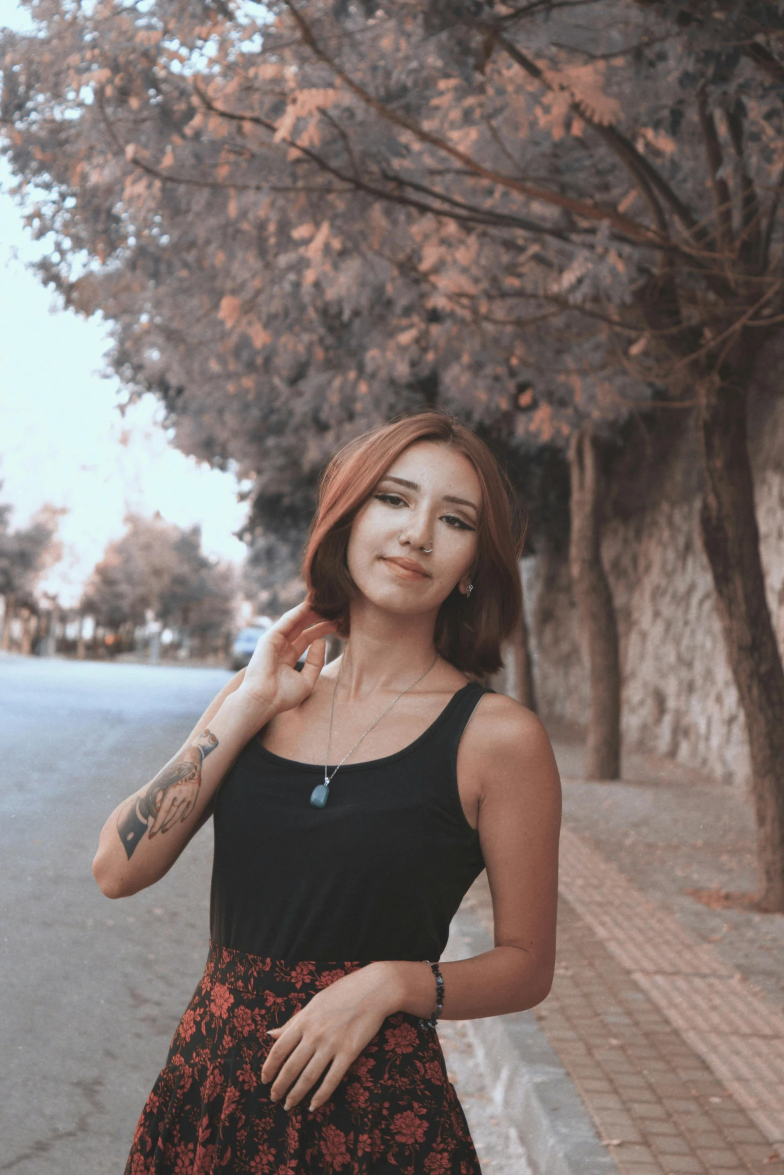 a woman standing next to some trees with an arm hanging down