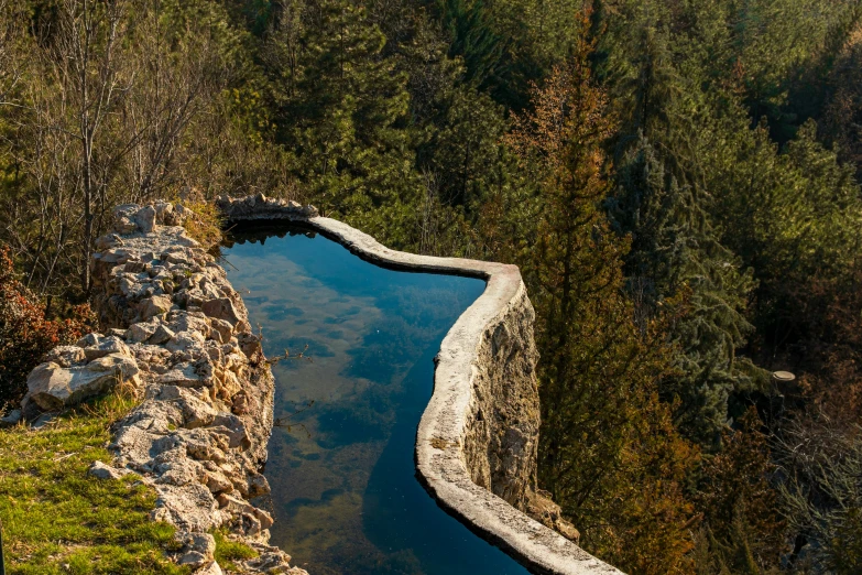 a pond sits between two stones in a green wooded area