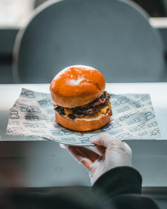 person's hand holding a hamburger in the middle of a table