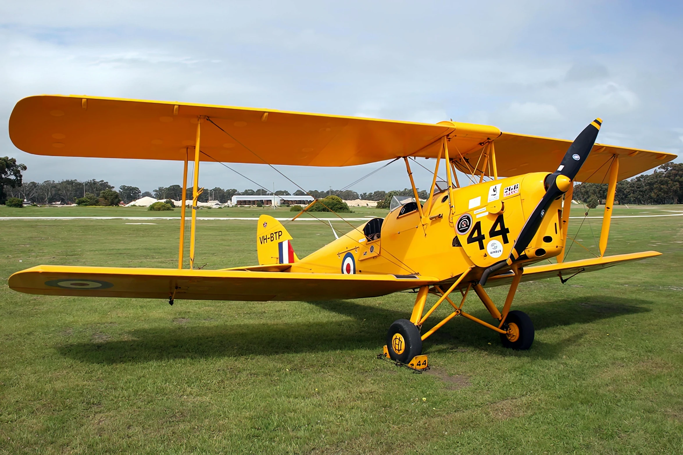 a small yellow airplane parked in the grass