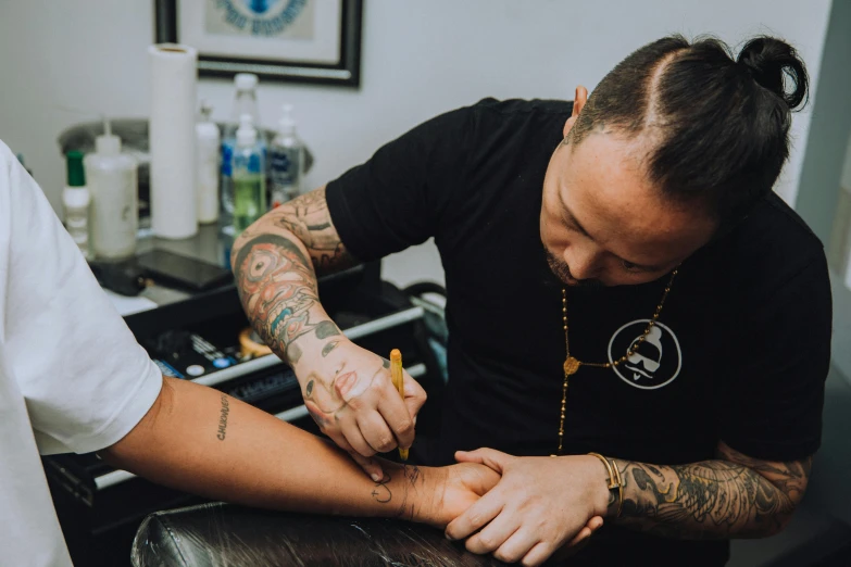 a tattooed man  another mans arm in a barbershop