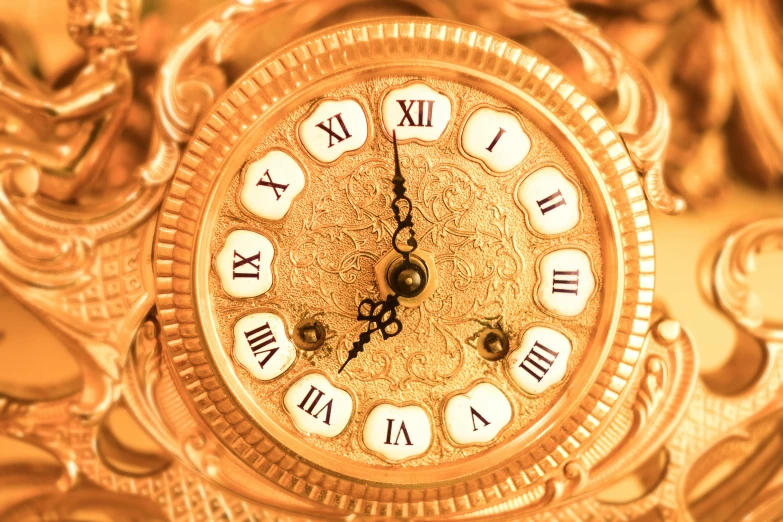 a gold clock with roman numerals on the face