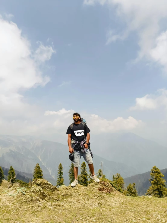 a man standing on top of a field near mountains