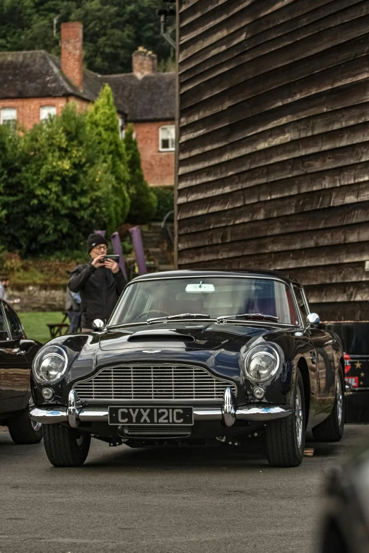 the man takes a po of the black classic car