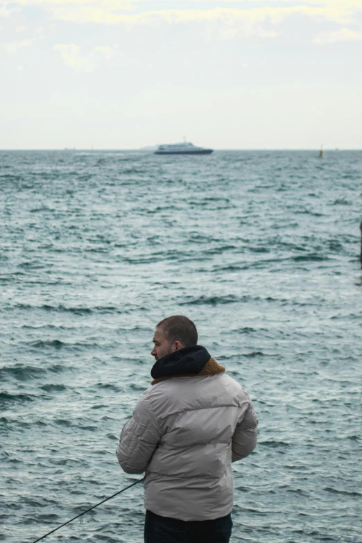 a woman on the shore fishing with a boat in the background