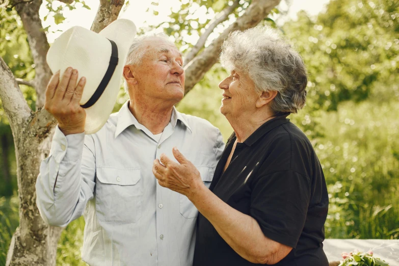 an older couple of people standing next to a tree