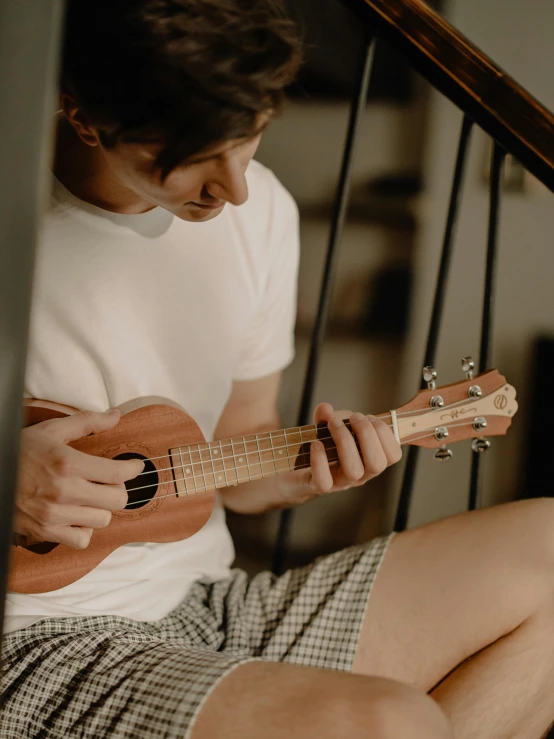 a young man is holding an ukulele in his lap