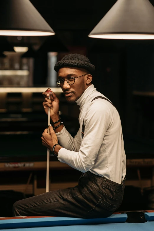 man in suspenders holding umbrella sitting on pool table