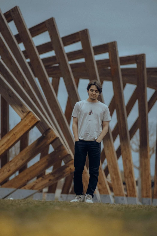 a man standing in front of a sculpture of wood beams