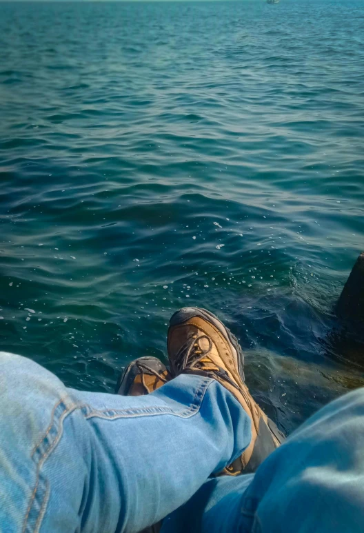 a person is sitting on the end of rocks looking at water