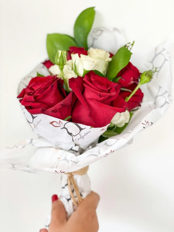 someone holding a bunch of red and white flowers