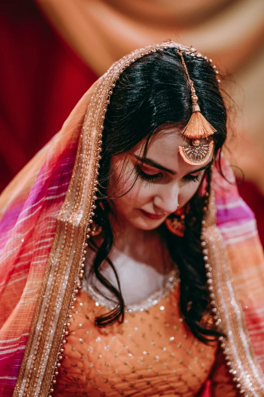 a beautiful indian woman in orange saree is posing