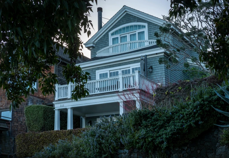 a white house sitting on the side of a lush green hillside