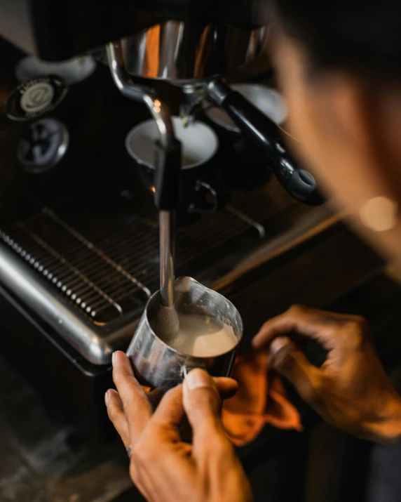 person stirring a cup of coffee with the help of a metal strainer