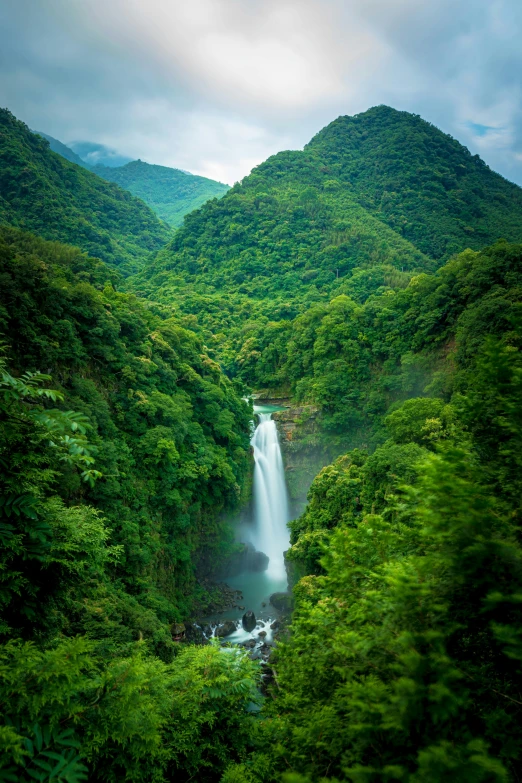 a very long flowing waterfall in the middle of a forest