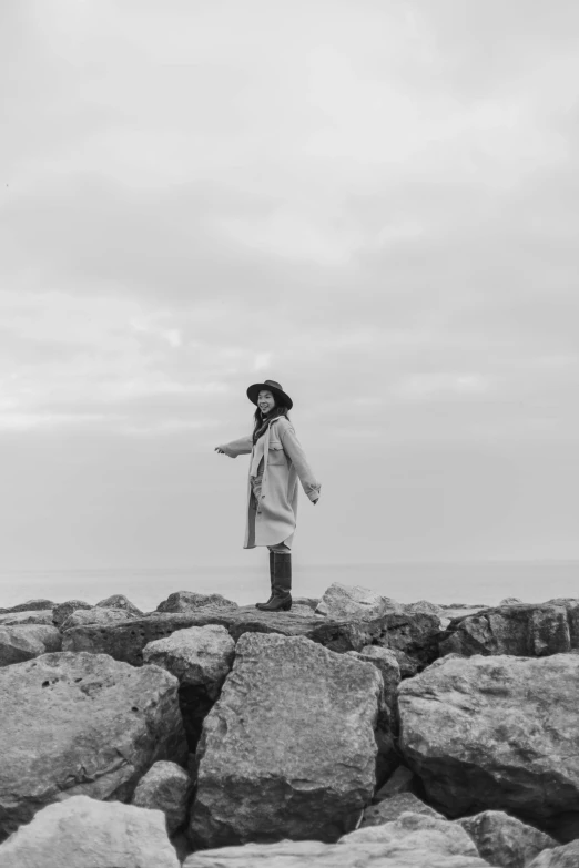 black and white pograph of person on a rocky shoreline