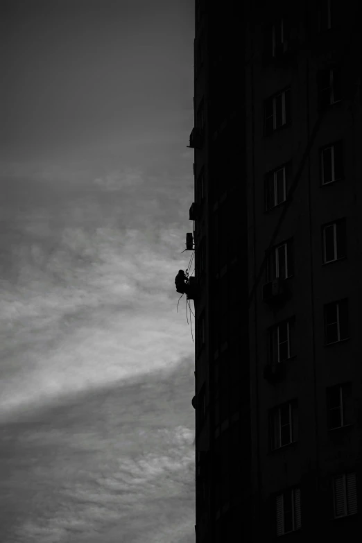 a dark silhouette of an apartment building with windows and an antenna