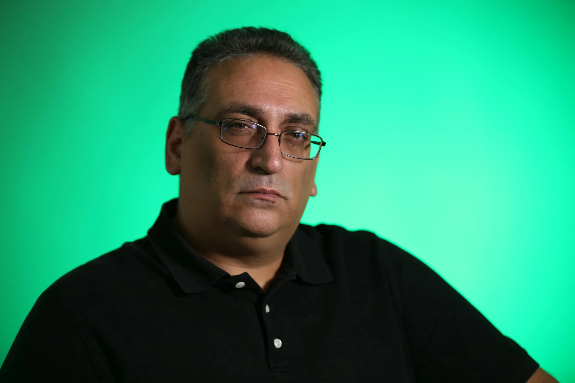 a man looking to his right in front of a green background