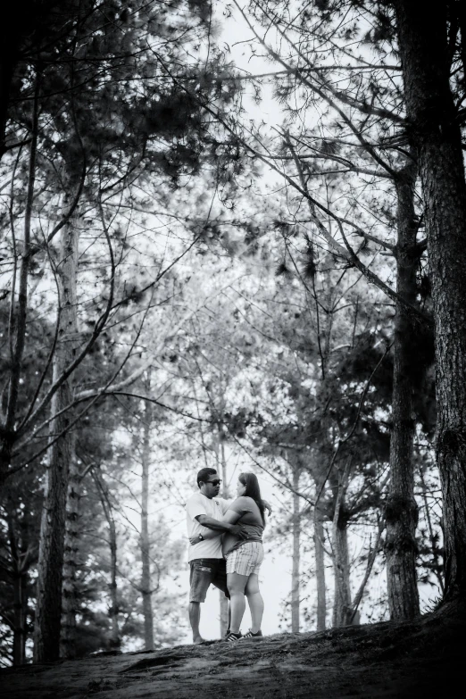 a couple stand together in the woods