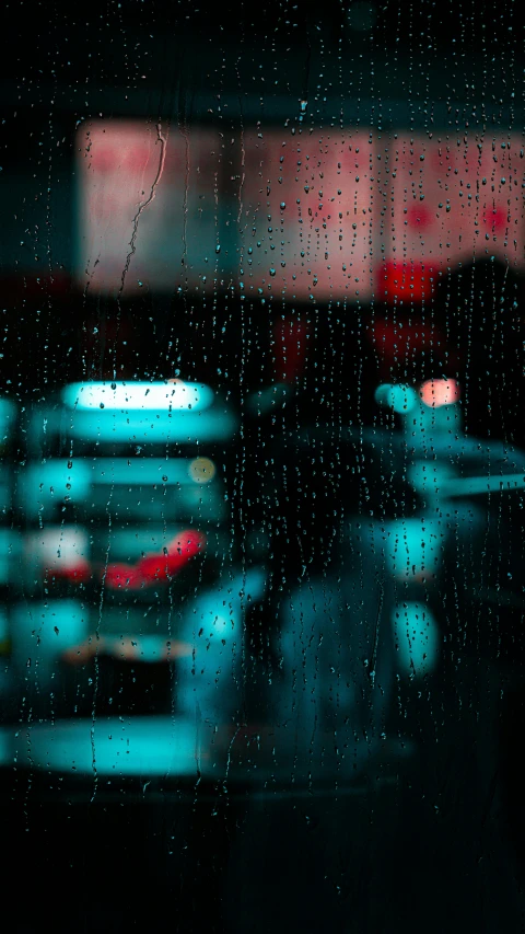 a dark background shows the rain drops on the window of cars