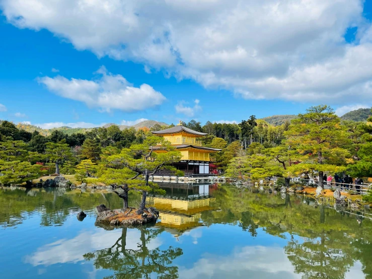 a large pond in front of a yellow building with trees