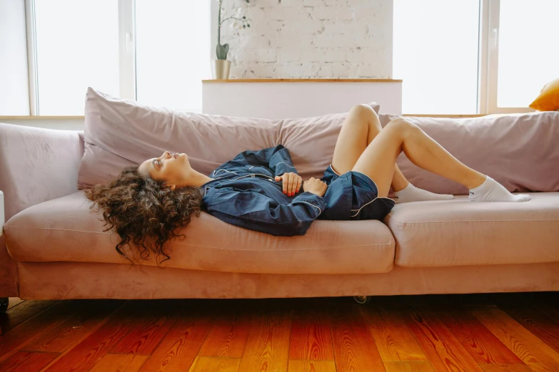 a woman is laying on a pink couch