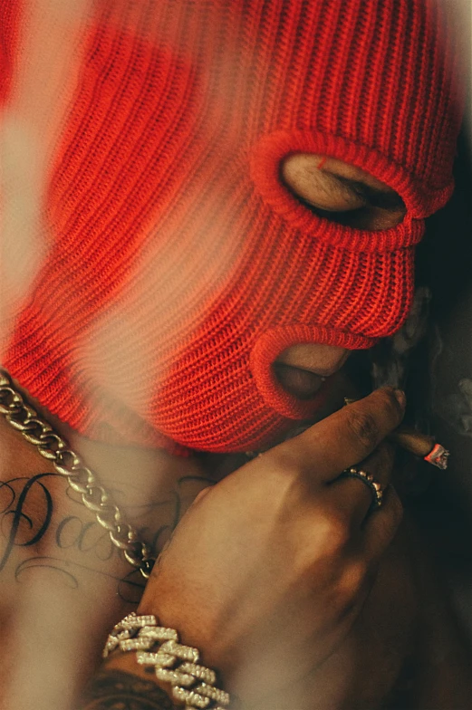 a person smoking a cigarette wearing a red knitted beanie
