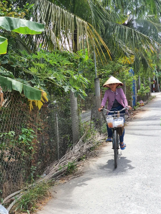 an asian woman riding a bicycle down a dirt road