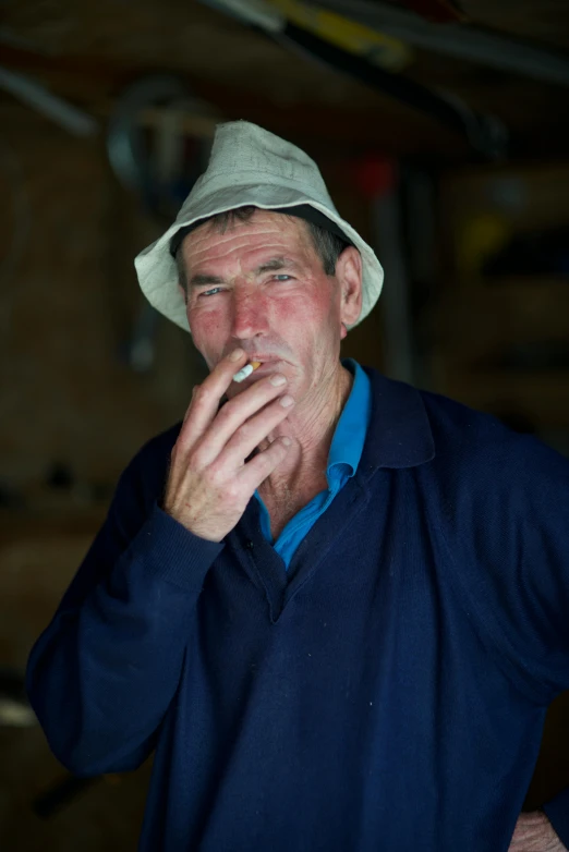 a man smoking a cigarette while wearing a hat