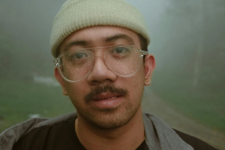 a man with glasses is standing in the rain