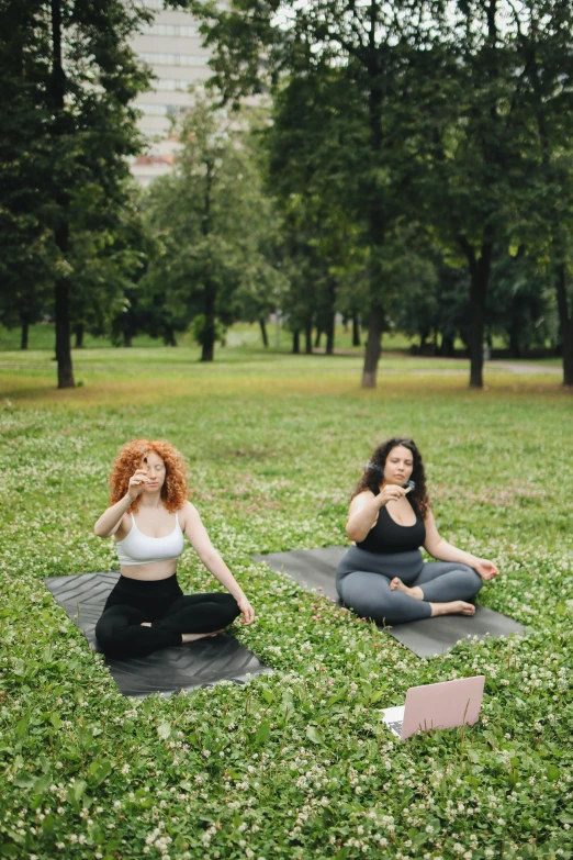 two women are doing yoga in the park