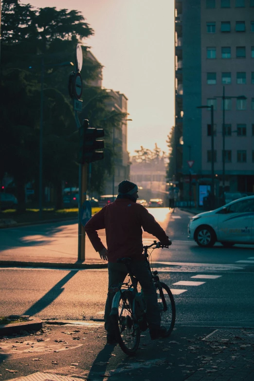 man on bicycle at intersection in city at sunset